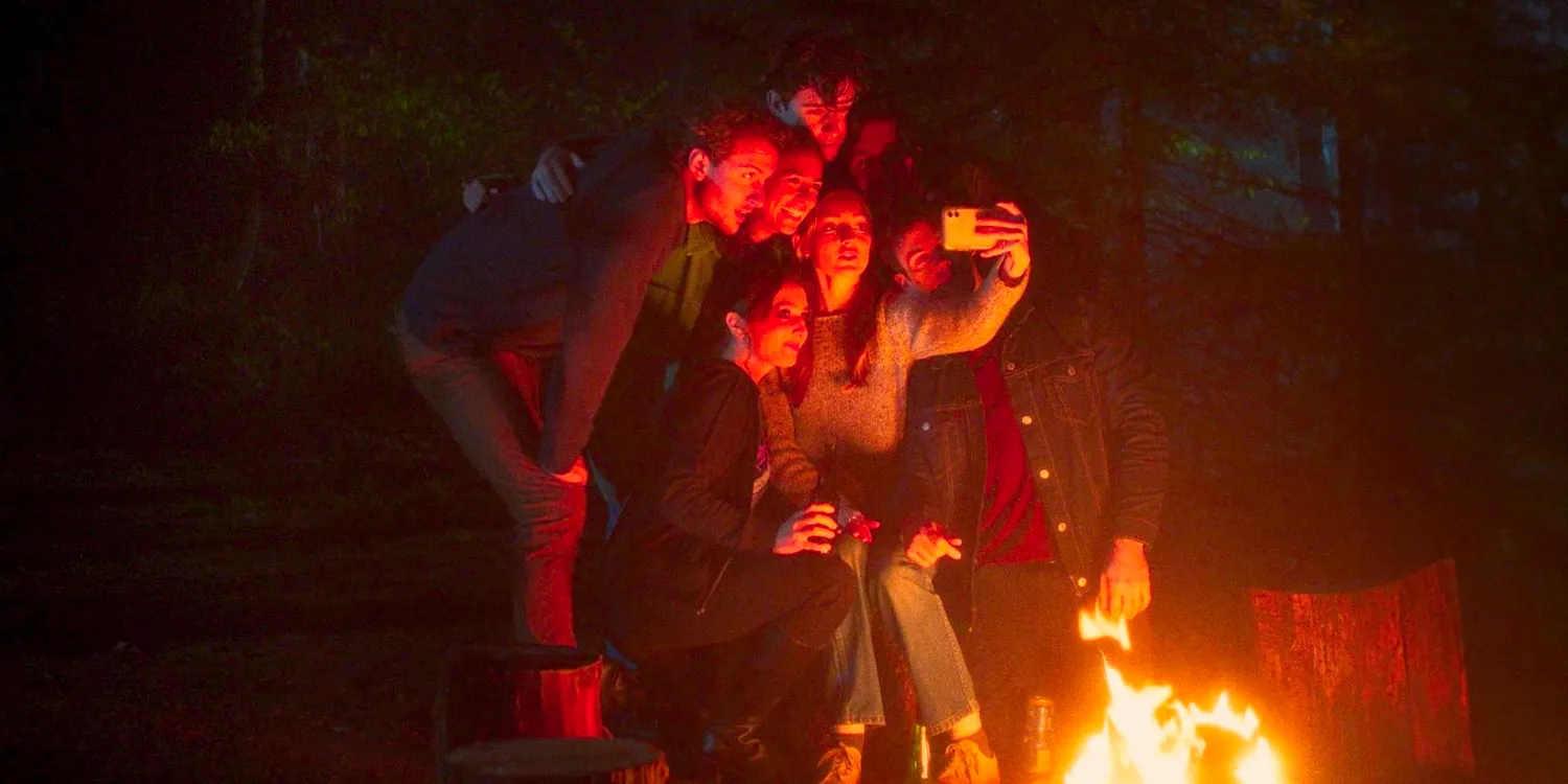 A group of friends taking a selfie in the woods around a campfire from In a Violent Nature (2024) Image