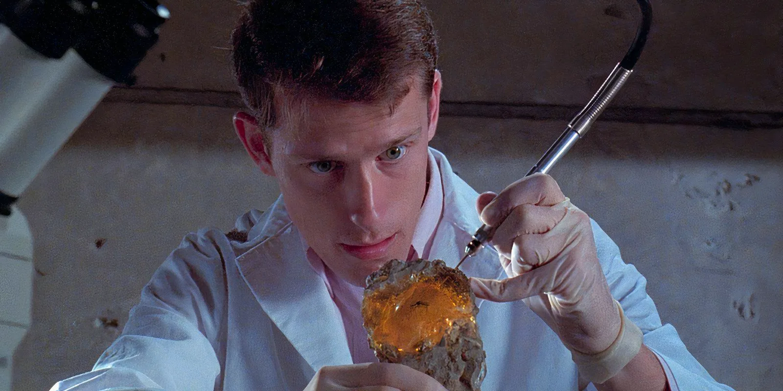 A scientist uses a tool on a mosquito encased in amber in Jurassic Park Image