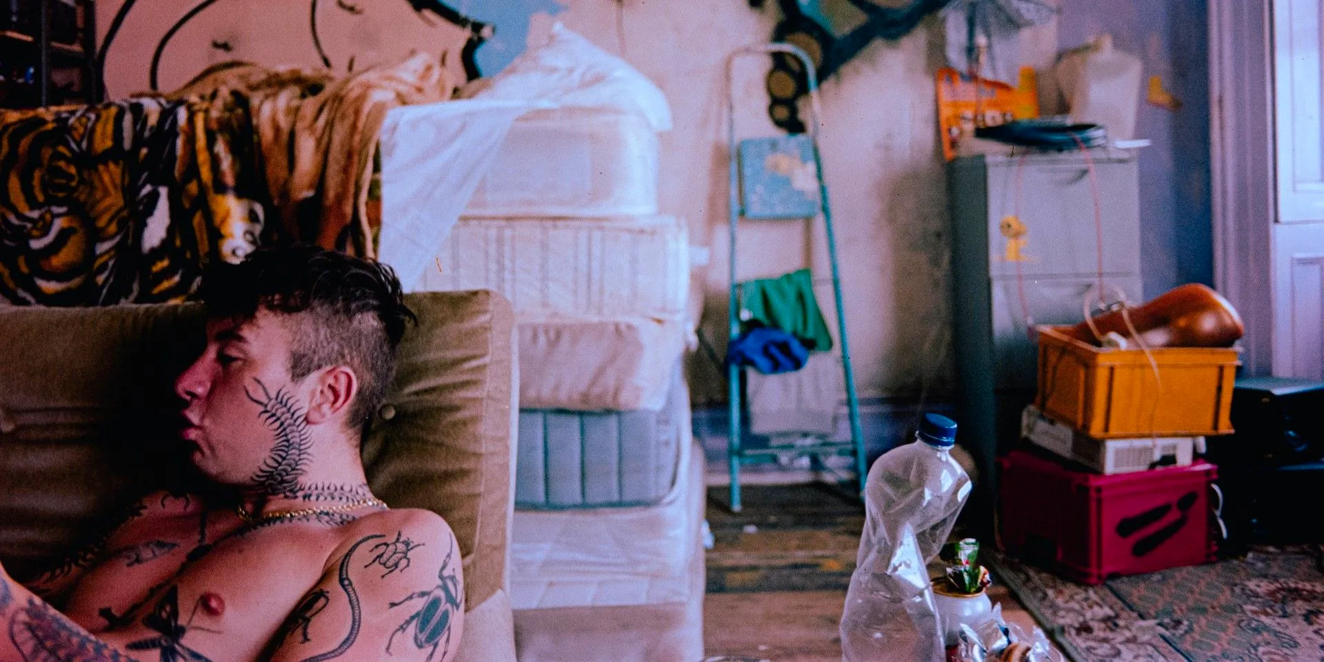 a tattooed Barry Keoghan lounging on a chair in Bird Image