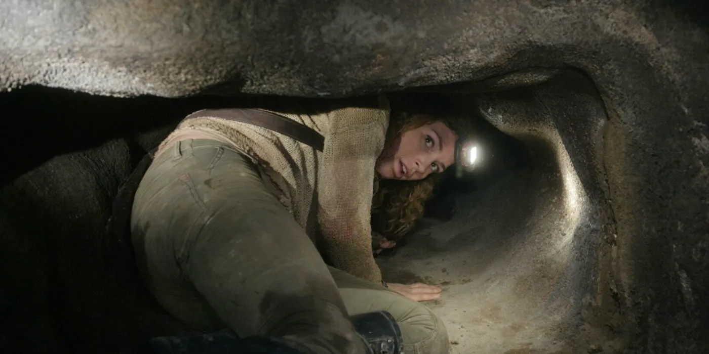 A woman crawls through a rock in As Above So Below Image