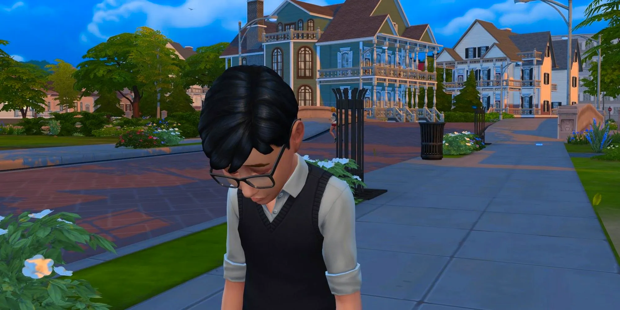 A young Sim from the Sims 4 standing on a sidewalk and looking very sad, with two mansions in the background. Image