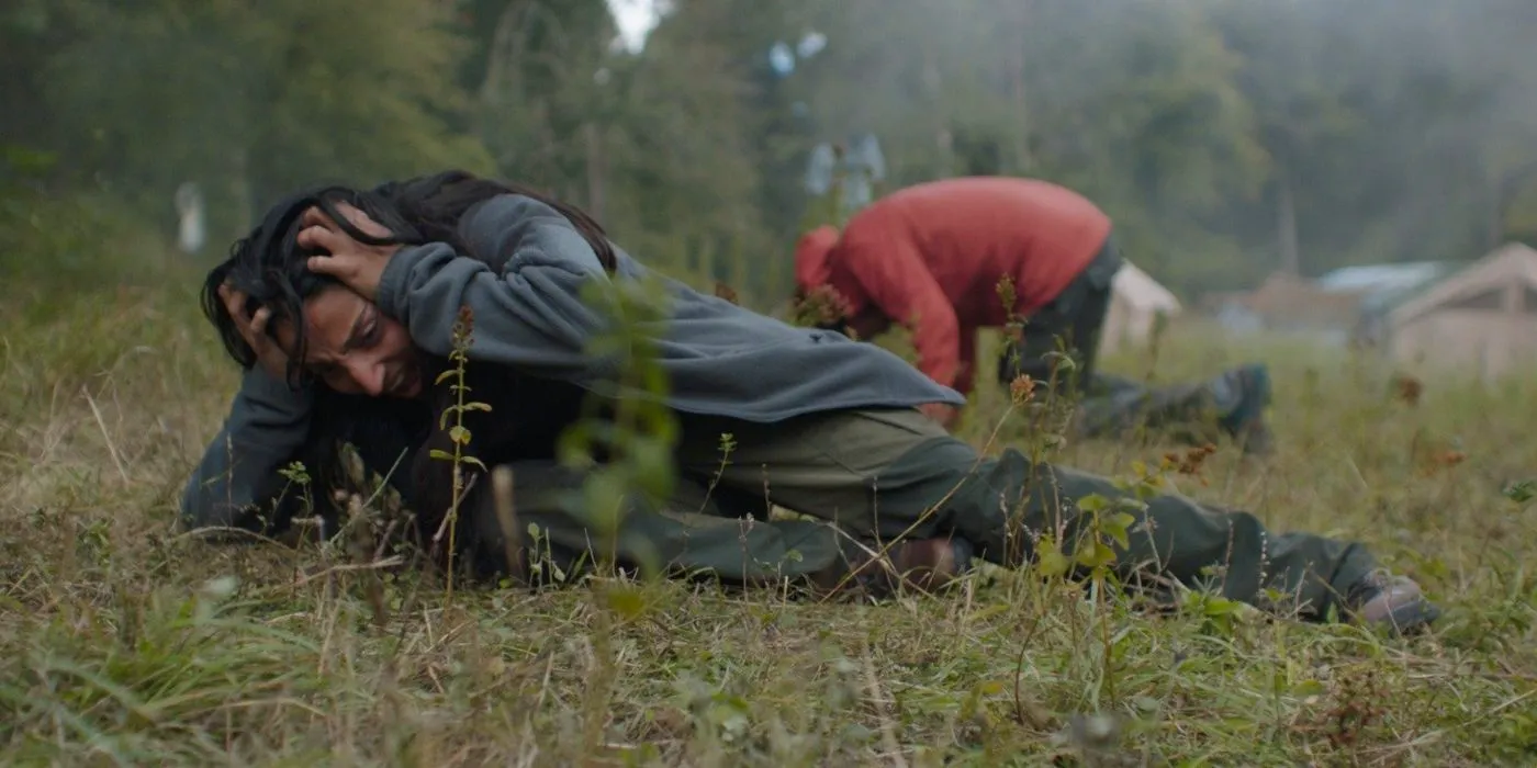 airborne violence in in the earth two people lie on the grass with their hands against their heads crying out in pain Image