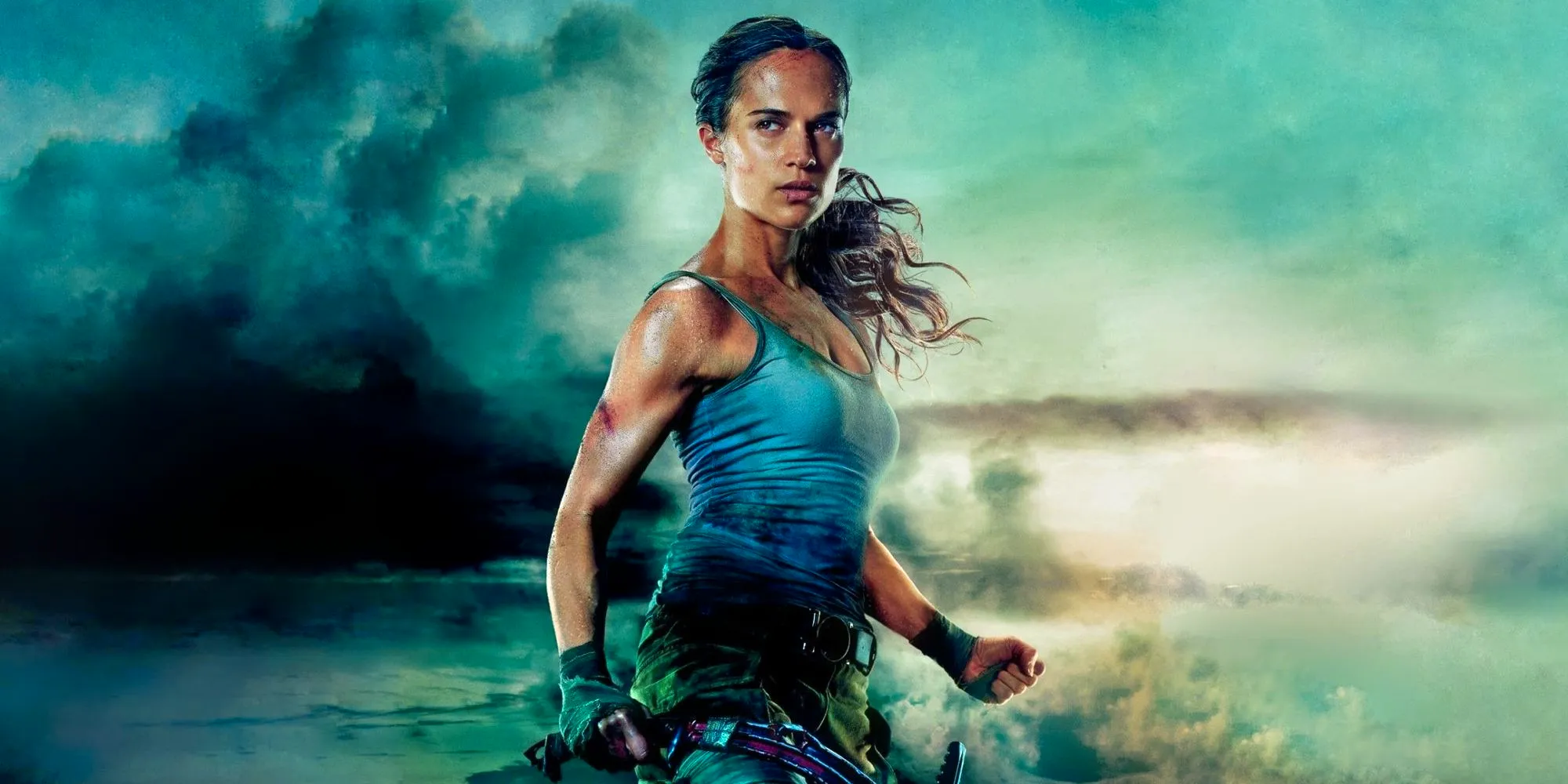 Alicia Vikander as Lara Croft clinching her fists while standing against stormy background in Tomb Raider Image