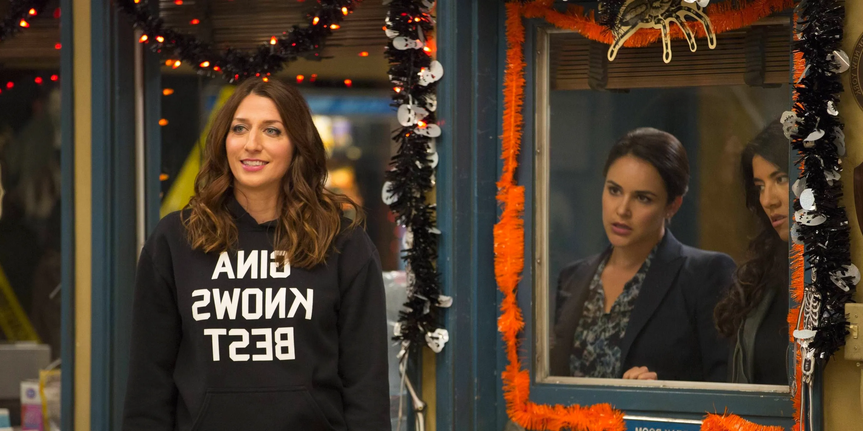 Amy and Rosa look at Gina from behind a door in Brooklyn 99 Image