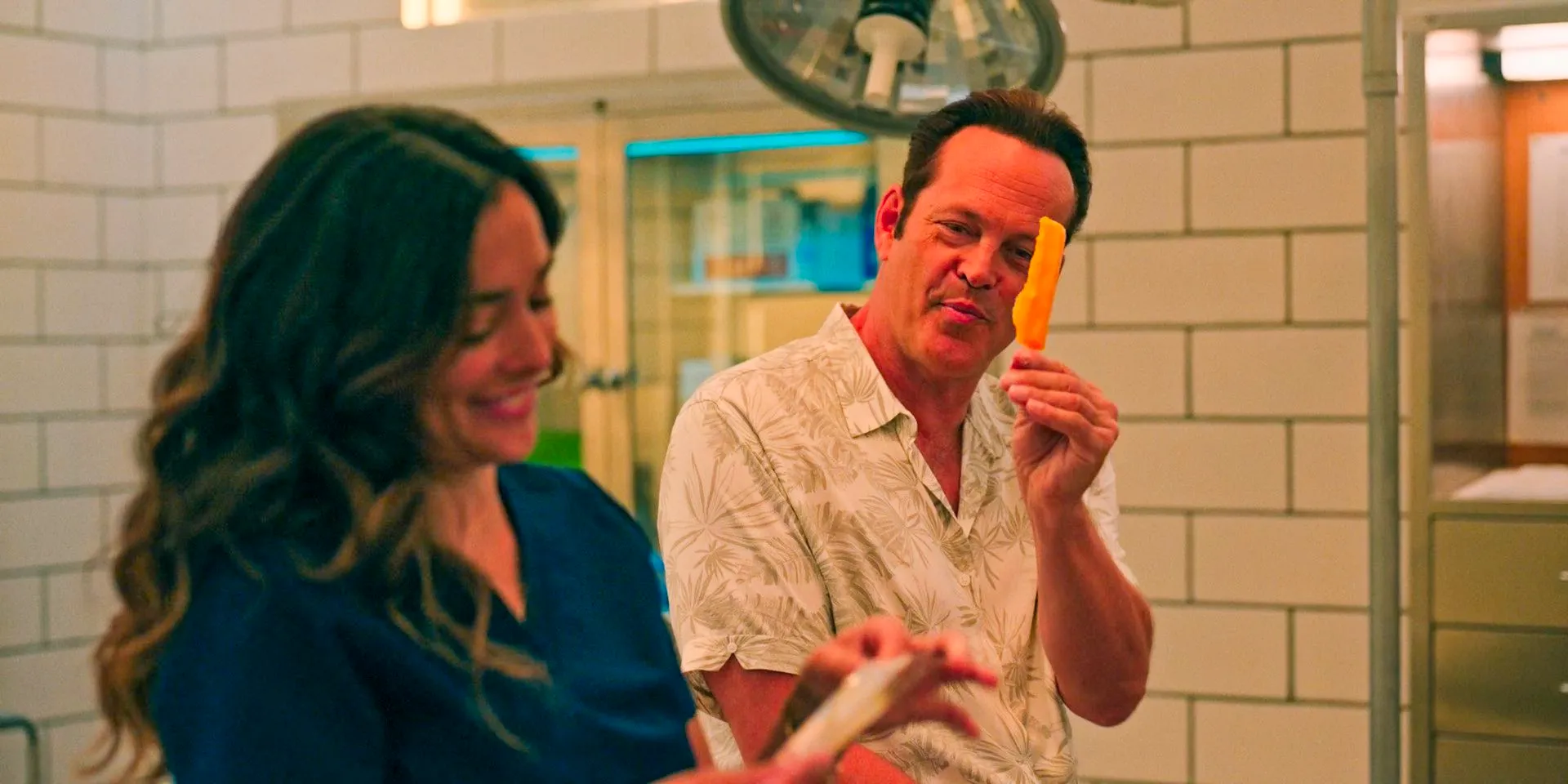 Andrew (Vince Vaughn) and Rosa (Natalie Martinez) sharing a mango ice pop in the morgue in Bad Monkey Season 1 Episode 4 Image