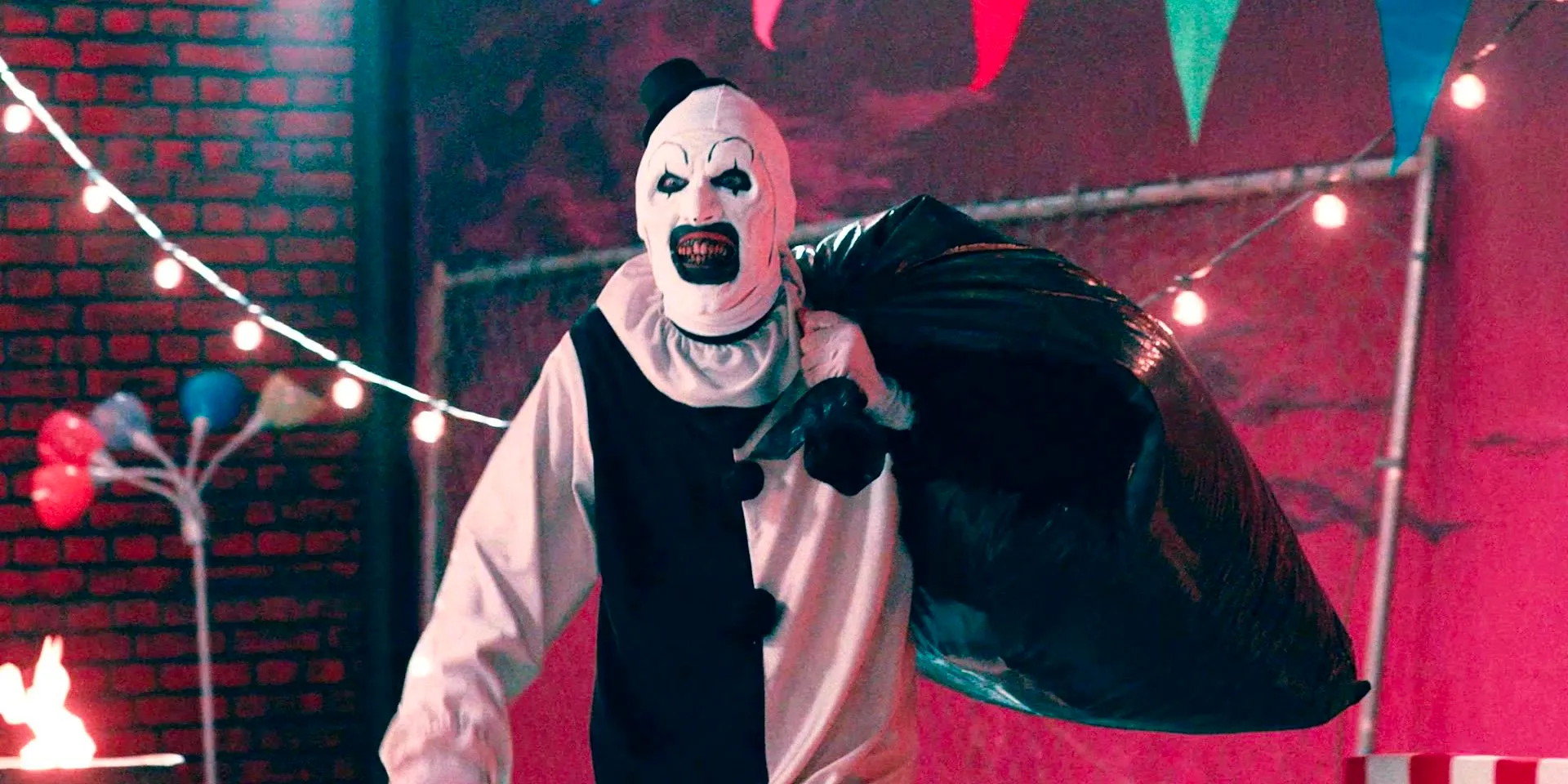 Art the Clown carrying a black trash bag in Terrifier 2 Image