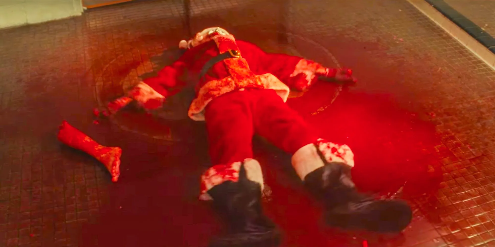 Art The Clown (David Howard Thornton) dressed as santa in a pool of blood and a severed leg making blood angels in Terrifier 3 Image