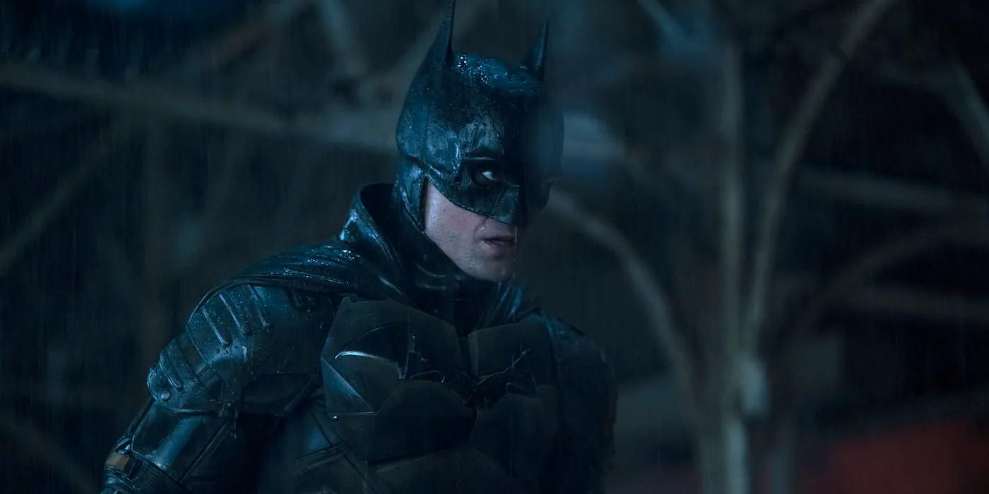 Batman in The Batman looking surprised at something offscreen in Gotham as it rains Image