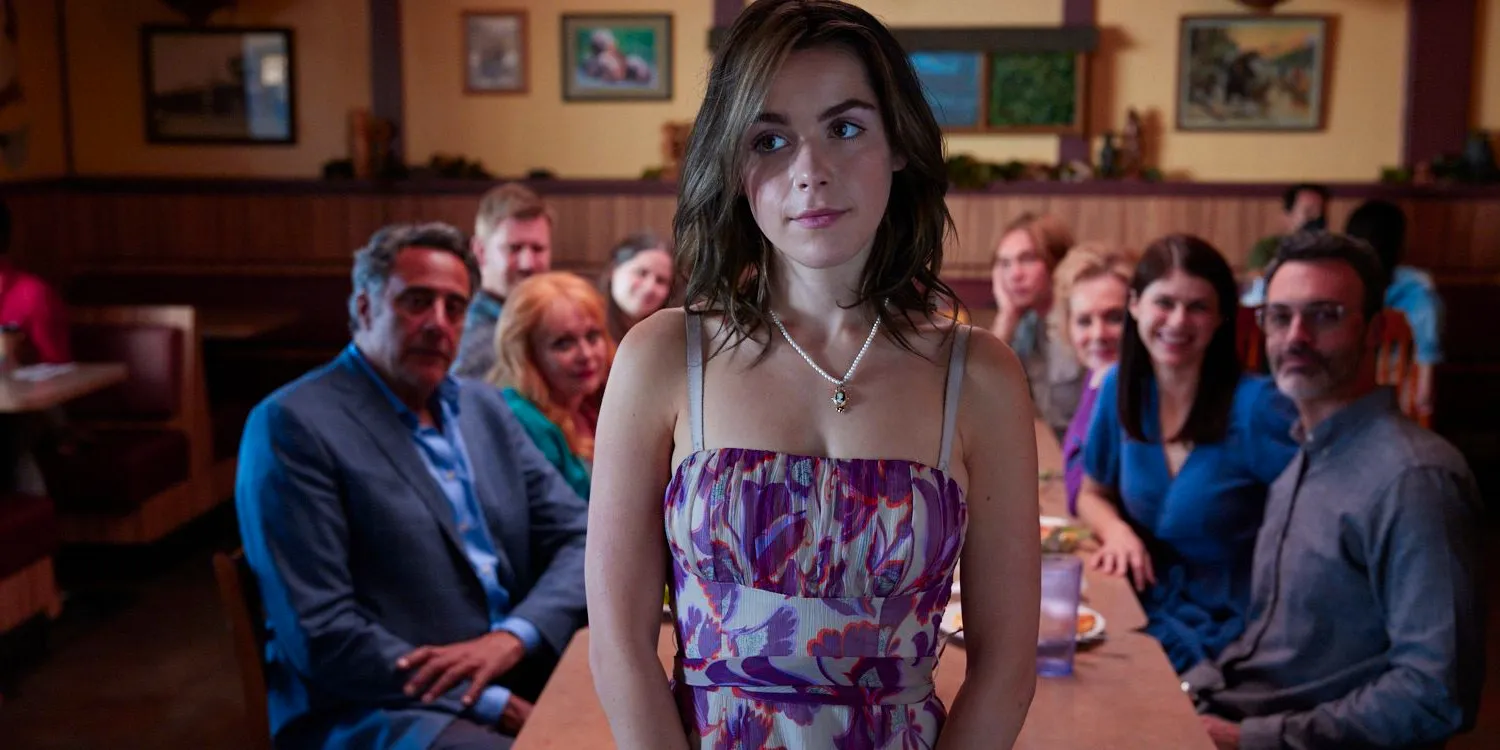 Bea stands in front of her entire family at a restaurant wearing a floral dress. Image