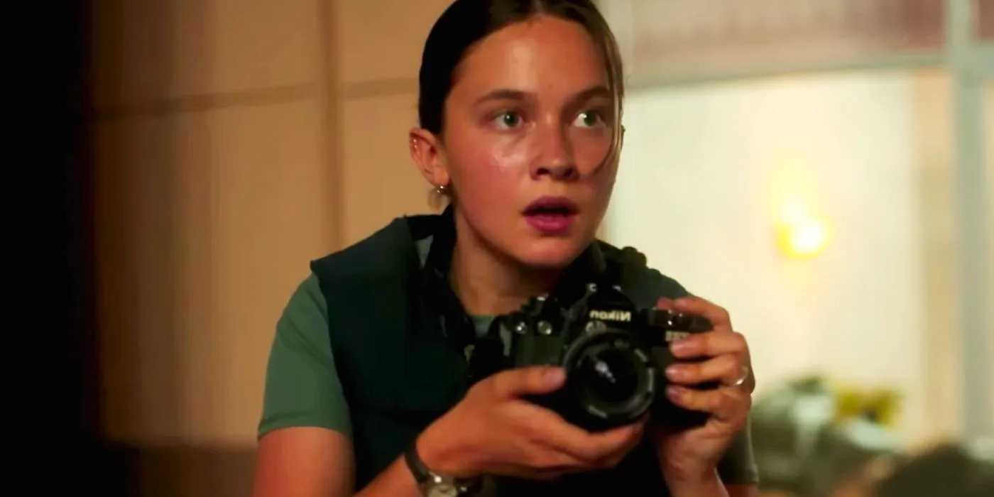 Cailee Spaeny as Jessie in Civil War. She is holding a camera, about to take a photo. Image