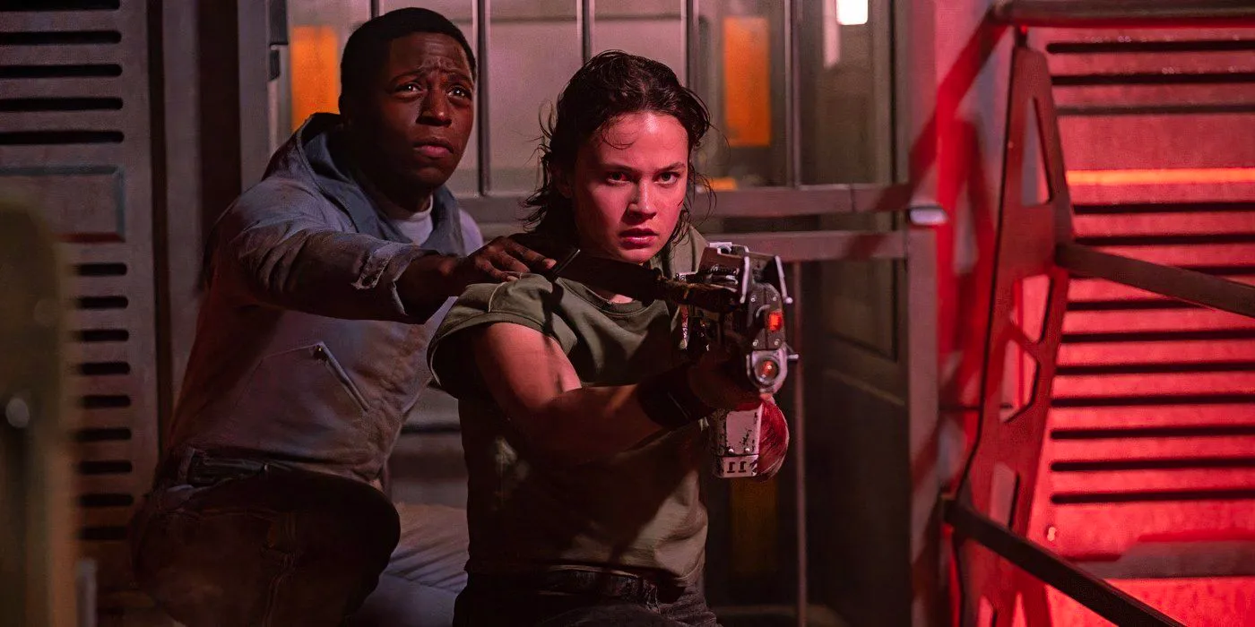 Cailee Spaeny as Rain points a gun while Andy stands behind her in Alien: Romulus Image