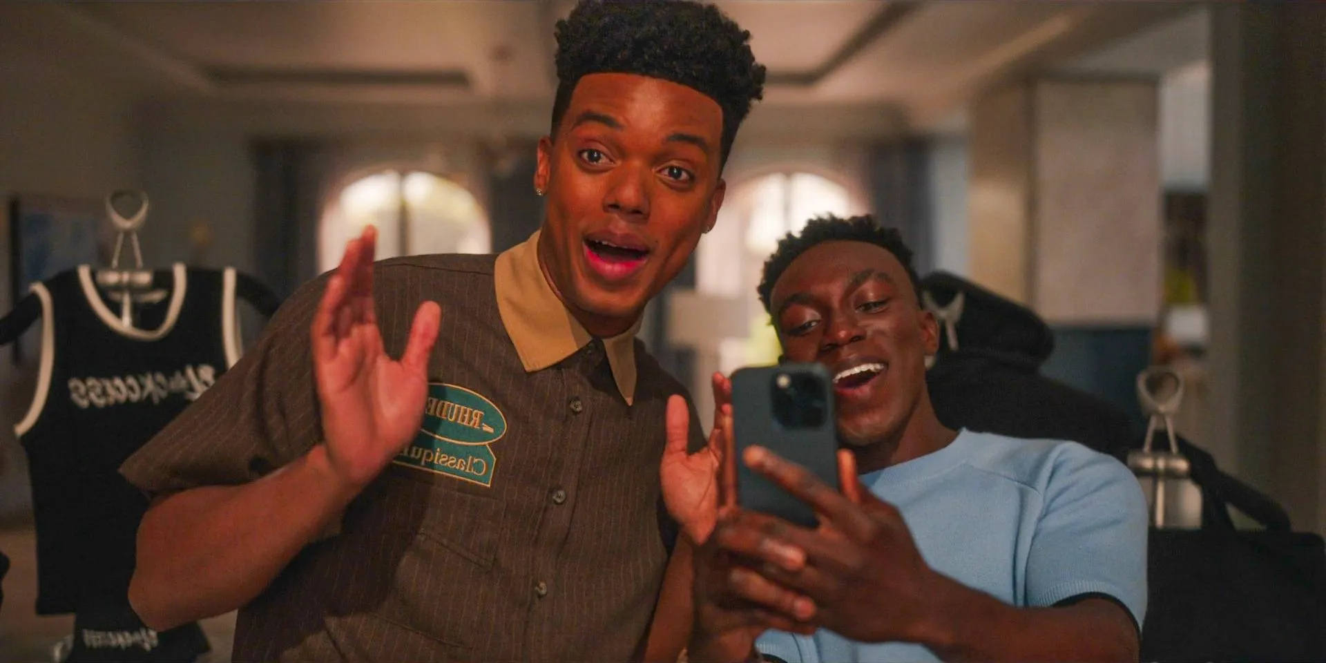 Carlton (Olly Sholotan) and Phil (Adrian Holmes) making a story of their mothers wearing Blackcess merch in Bel-Air Season 3 Episode 6 Image