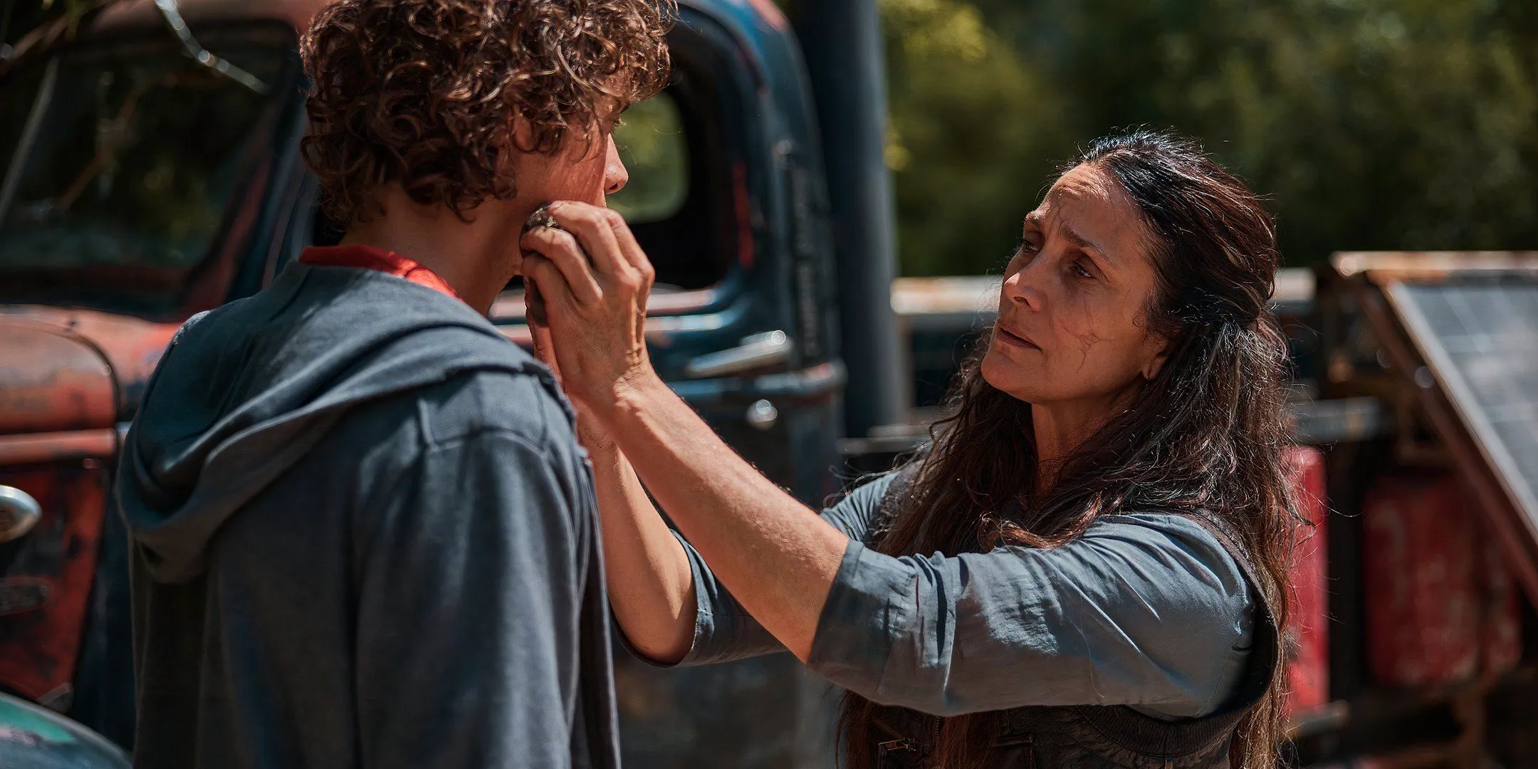 Carrie-Anne Moss as Mae looking worried and cleaning off Douglas Smith's face in Die Alone Image