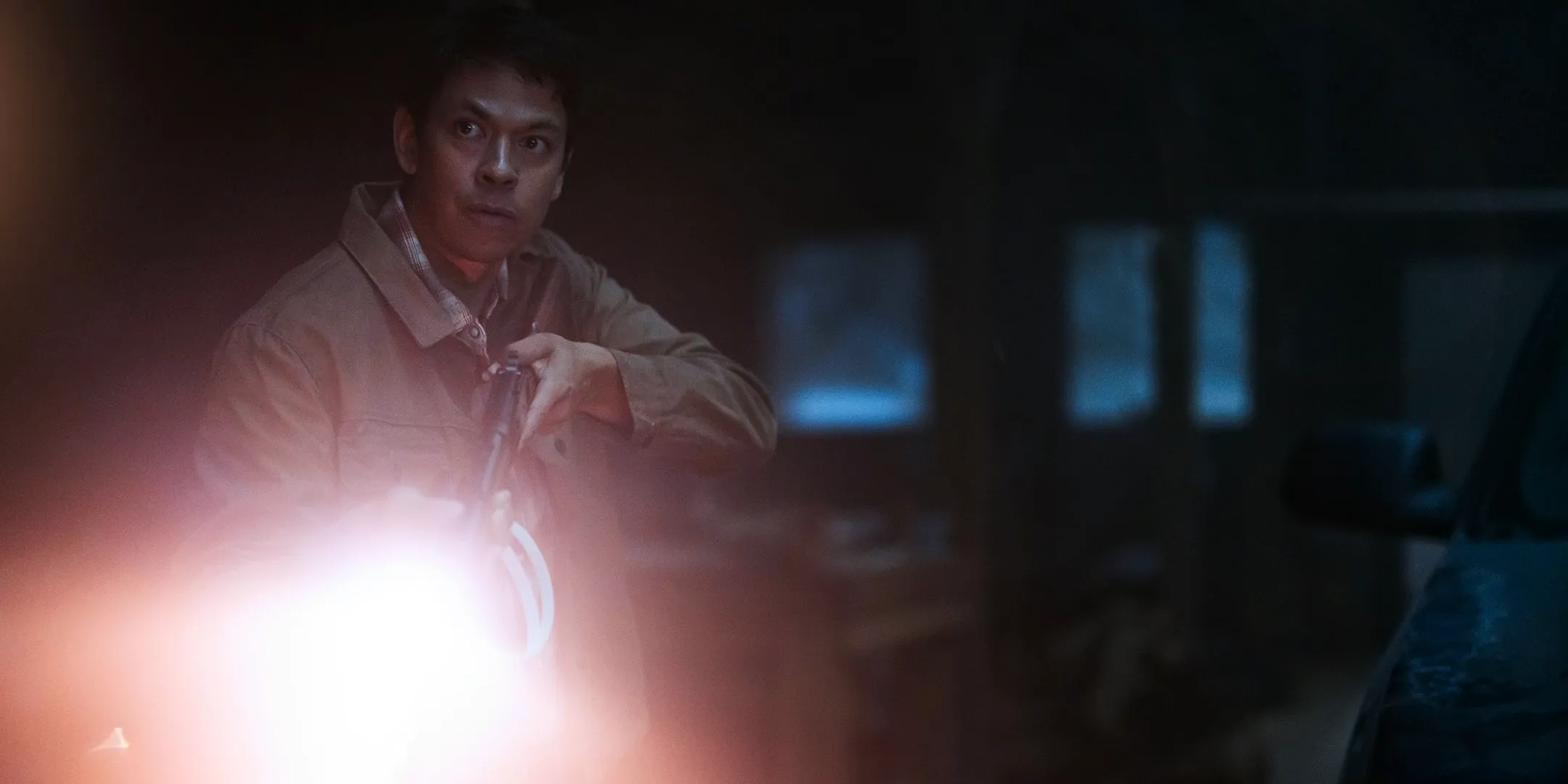 Chaske Spencer as Ruben looking intensely while aiming his rifle and flashlight in Teacup Image