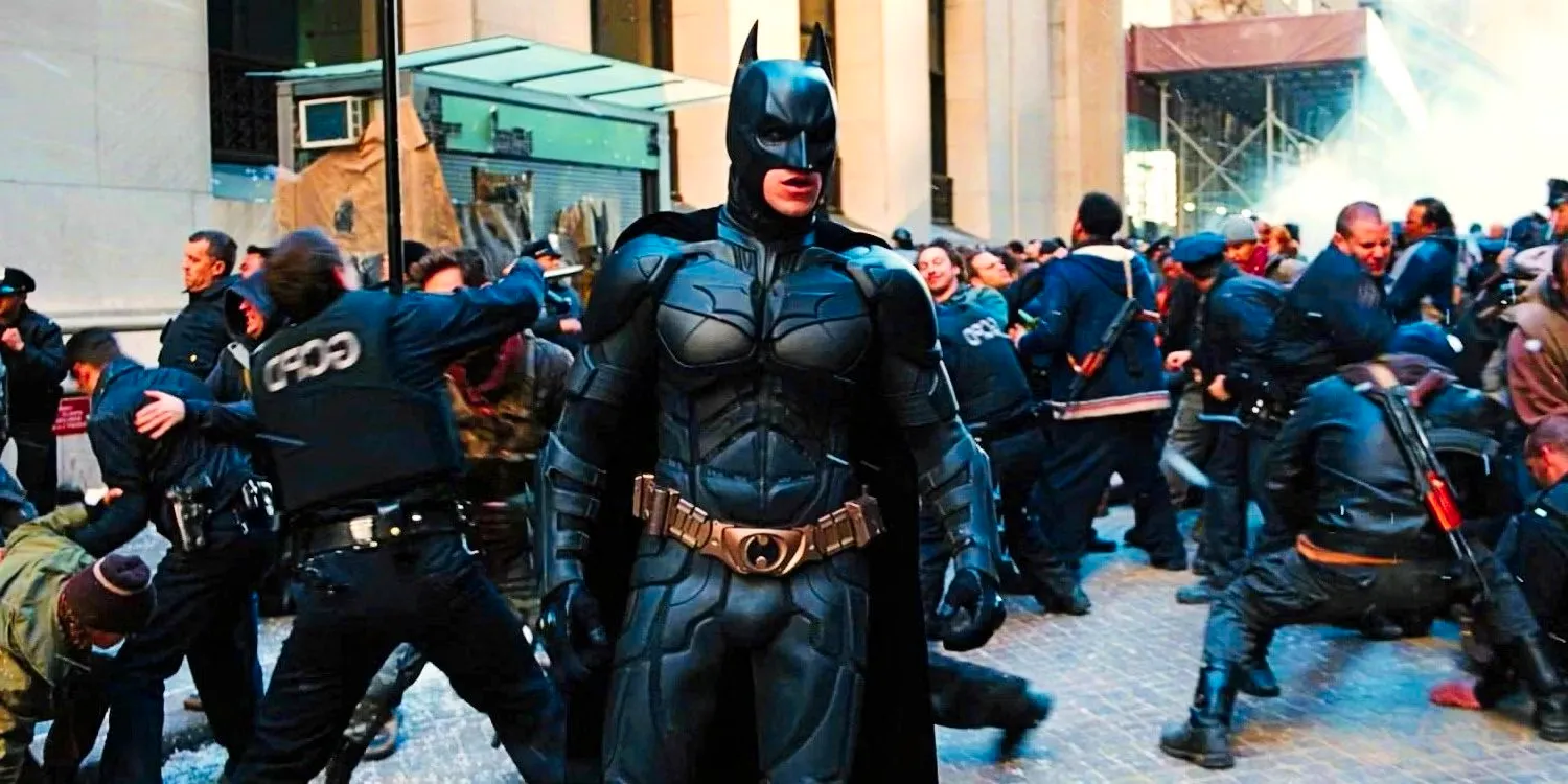 Christian Bale's Batman standing in the middle of a riot on the streets in The Dark Knight Rises Image