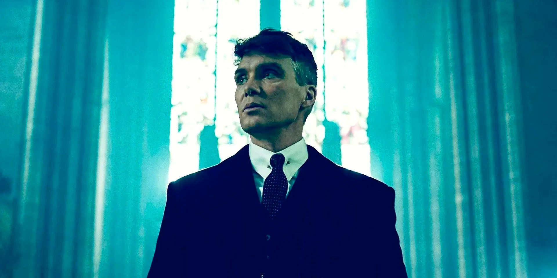 Cillian Murphy as Tommy Shelby looking to the side while standing in a church in Peaky Blinders Image