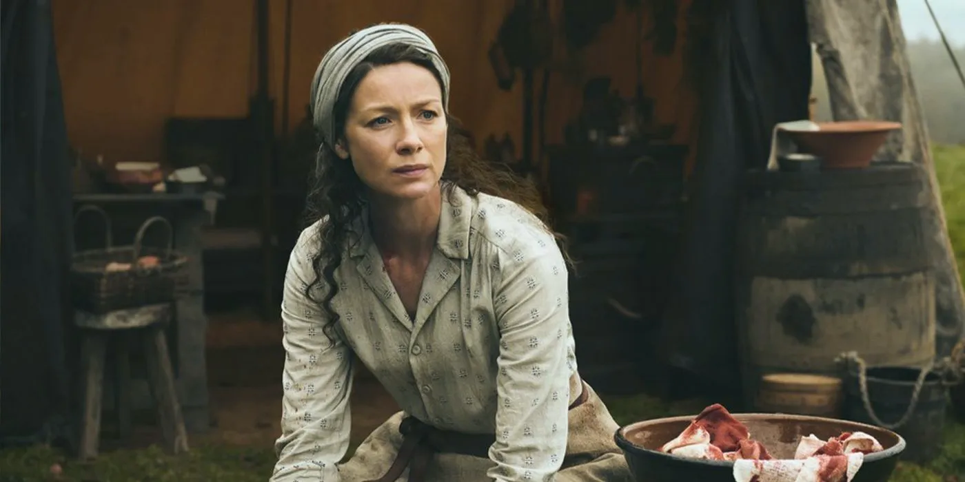 Claire outside cleaning blood from her tent in Outlander Image