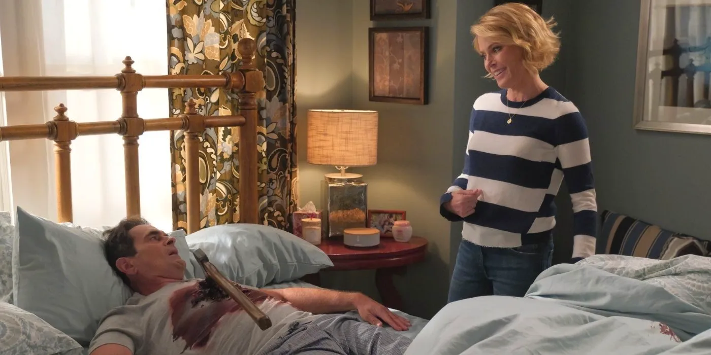 Claire standing over Phil who has a fake ax in his stomach on Modern Family Image