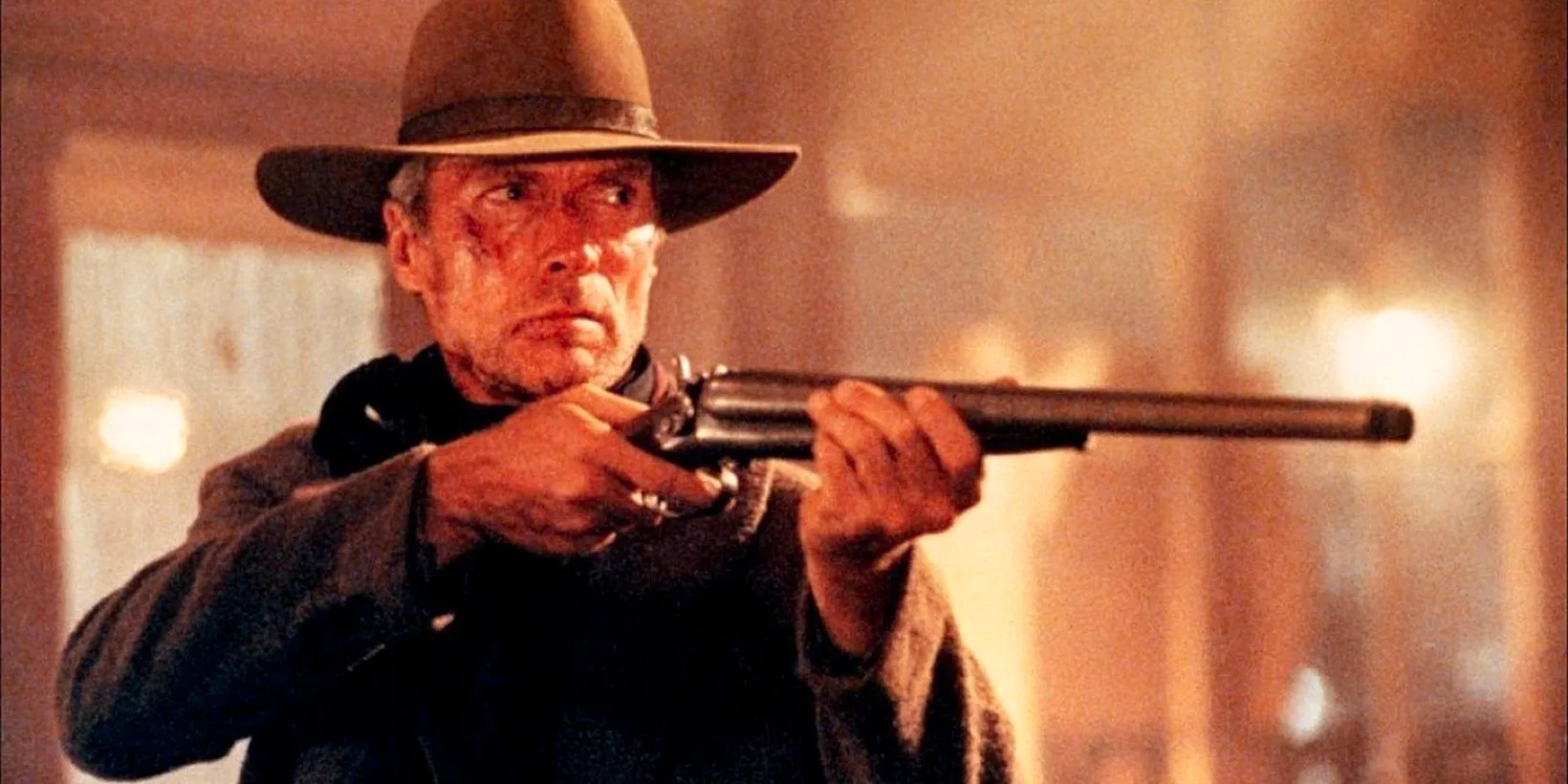 Clint Eastwood as Will Munny holding up a rifle in Unforgiven Image