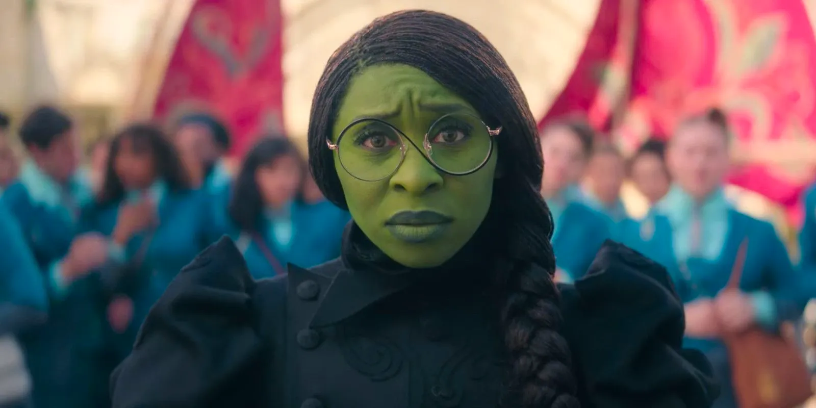 Cynthia Erivo as Elphaba arriving in Emerald City, wearing glasses and looking concerned in Wicked. Image