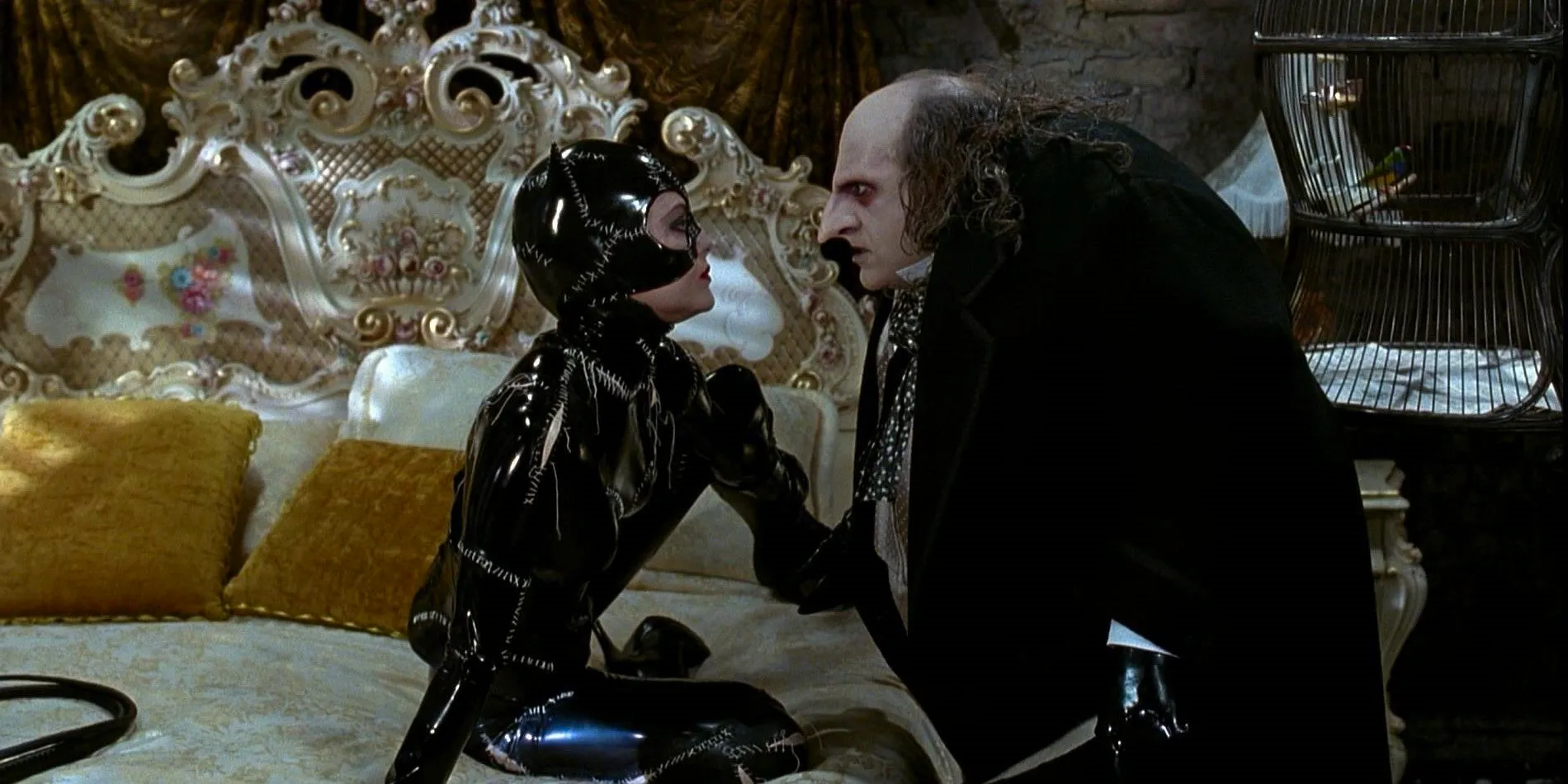 Danny DeVito as Oswald Cobblepot Penguin and Michelle Pfeiffer as Selina Kyle Catwoman sit on a bed in Batman Returns Image