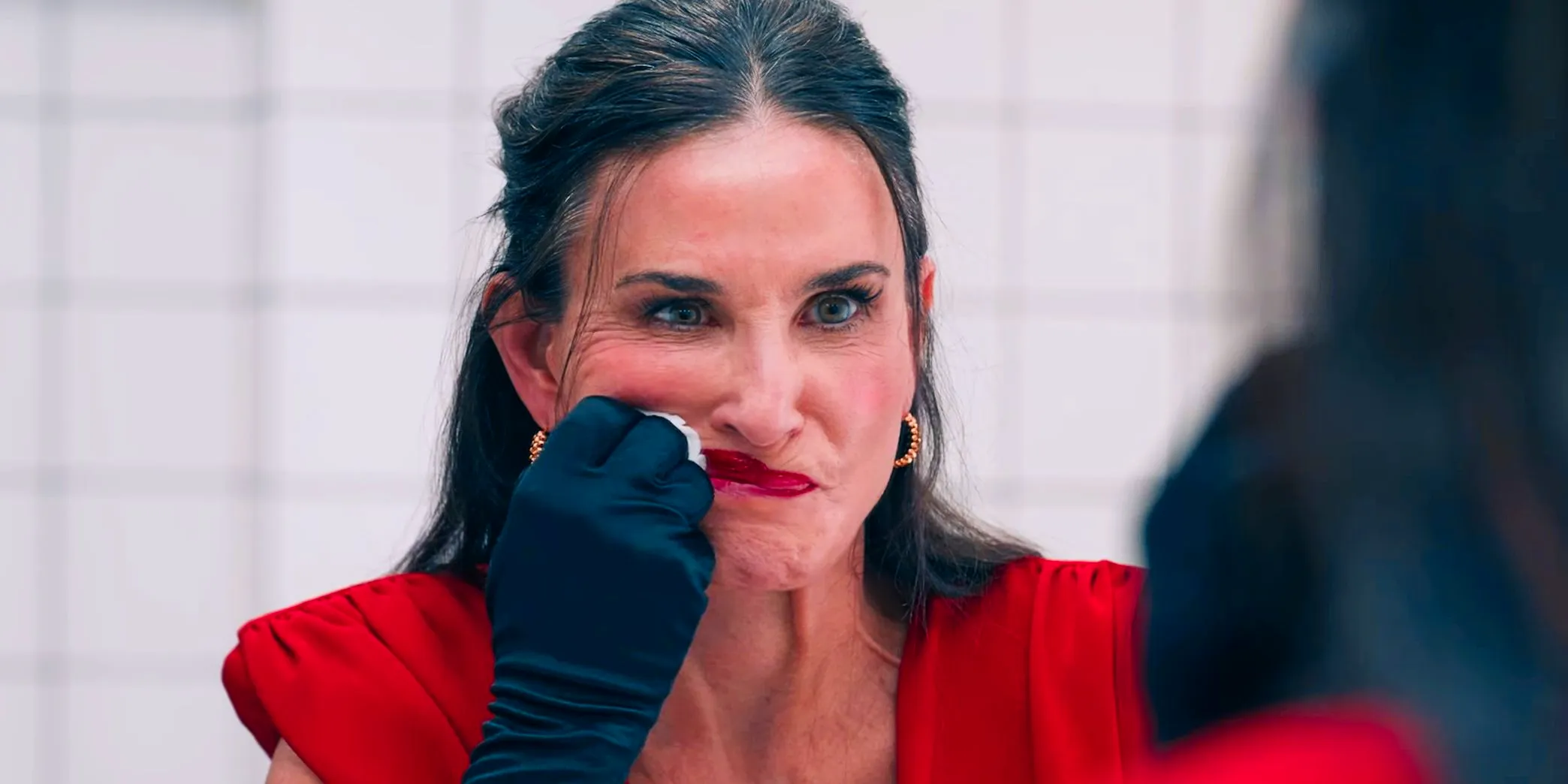 Demi Moore angrily smears her lipstick in the mirror in The Substance  Image