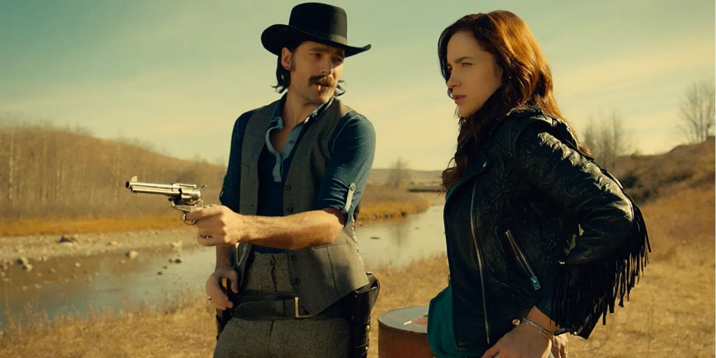 Doc Holliday holding a pistol next to Wynonna Earp on the side of a river bank Image