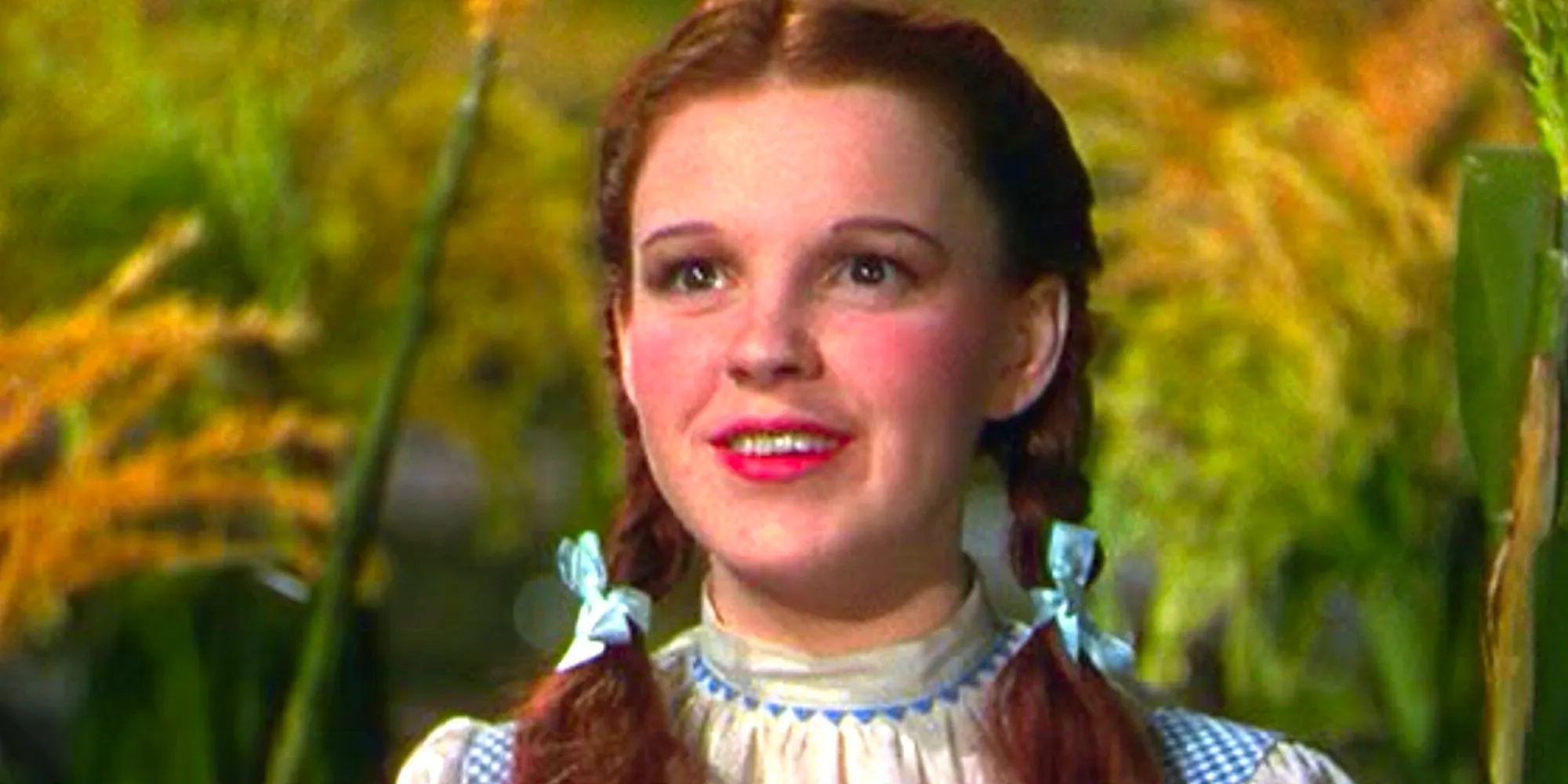 Dorothy (Judy Garland) smiling in a corn field in The Wizard of Oz (1939). Image