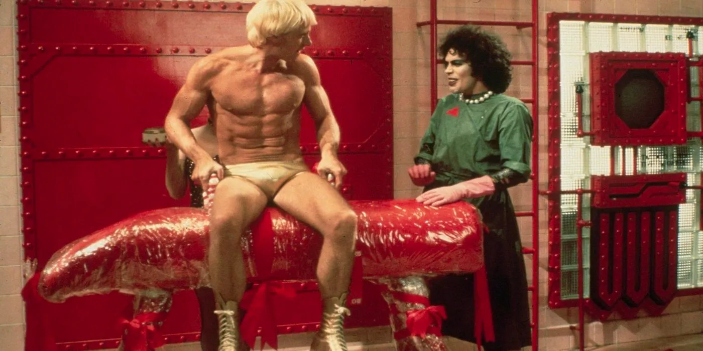 Dr. Frank-N-Furter standing while Rocky is seated, watching him, in Rocky Horror Image