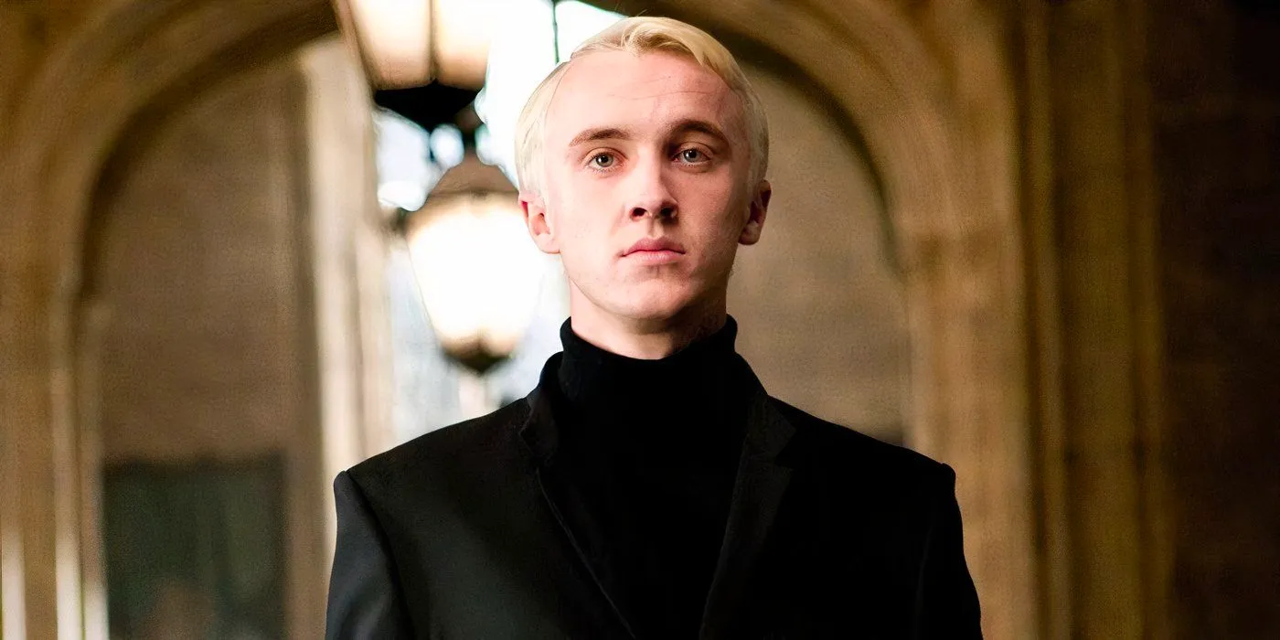 Draco Malfoy wearing a black suit and looking serious at Hogwarts Image