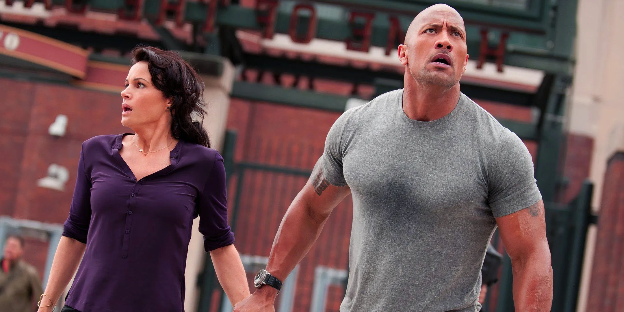 Dwayne Johnson as Ray and Carla Gugino as Emma looking worried and holding hands in San Andreas Image