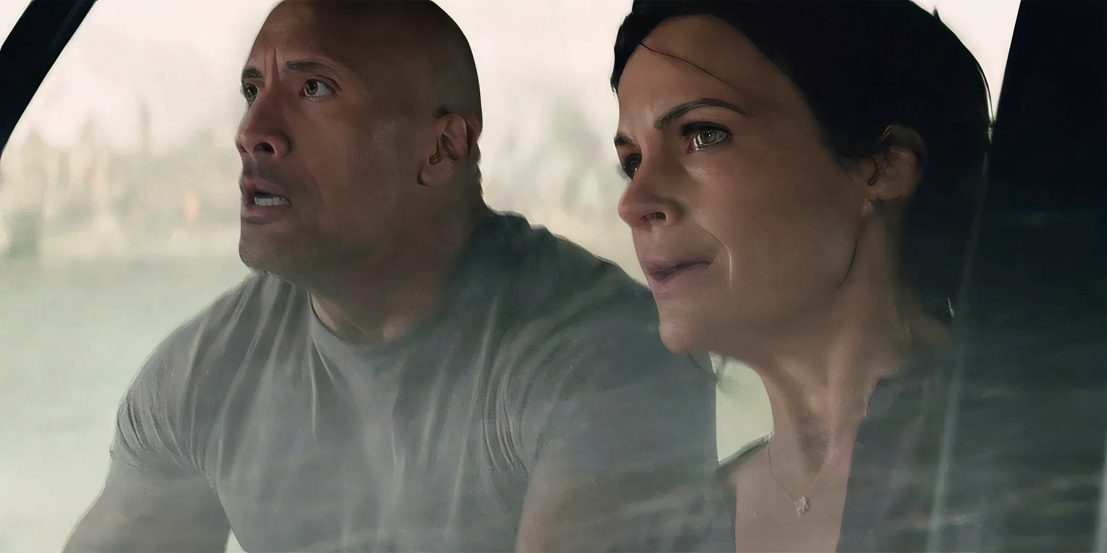 Dwayne Johnson as Ray and Carla Gugino as Emma looking worried while driving a boat in San Andreas Image