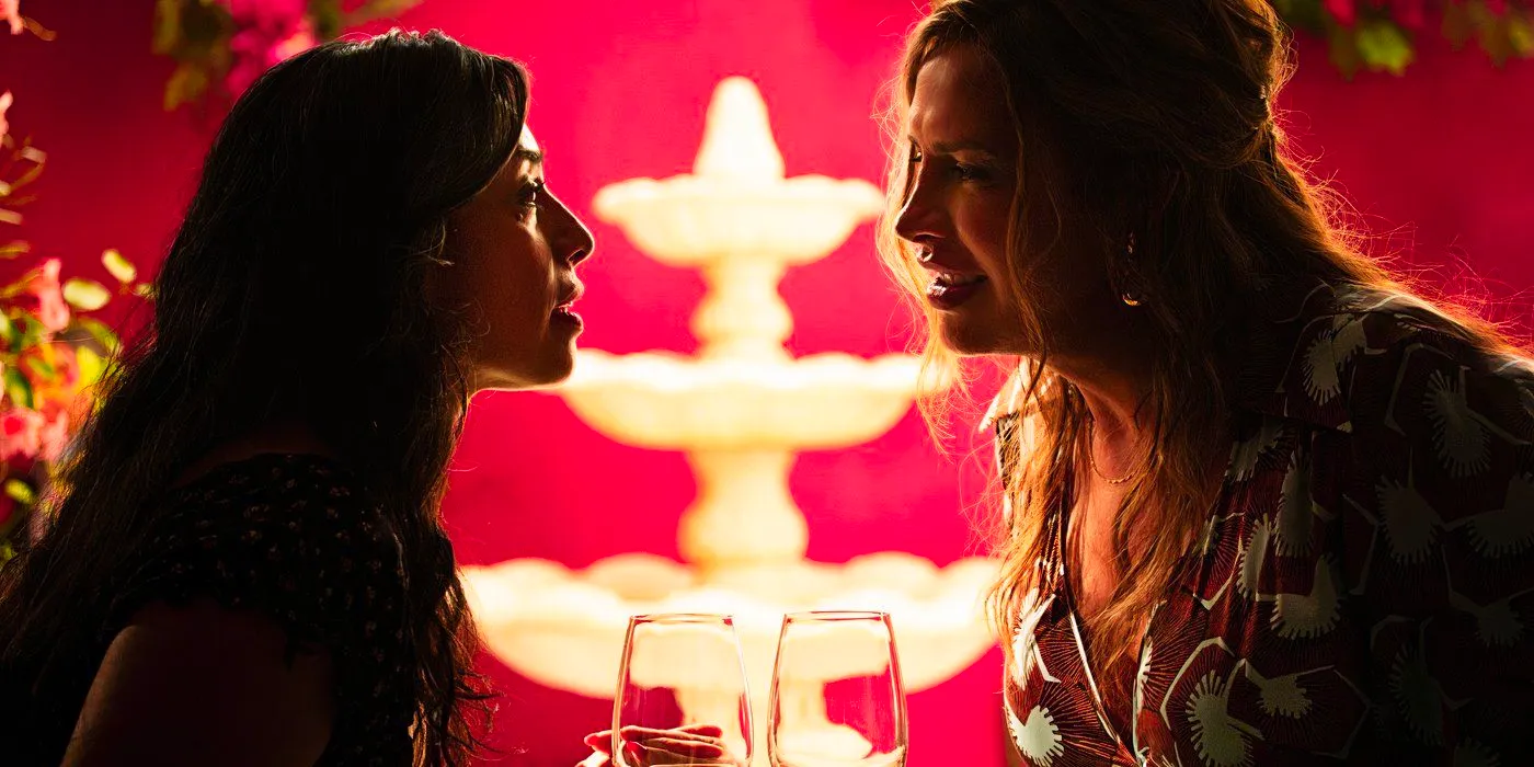 Emilia and Epifamía stare at each other across the table while on a date with a fountain in the background in Emilia Perez Image