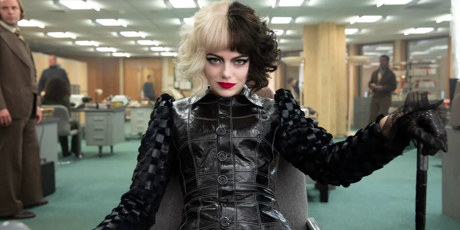 Emma Stone as Cruella smiles in an office with a cane in Cruella Image