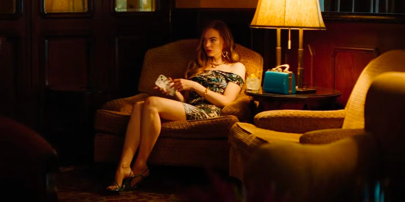 emma stone sitting in a chair in a dimly lit room in the kinds of kindness trailer Image