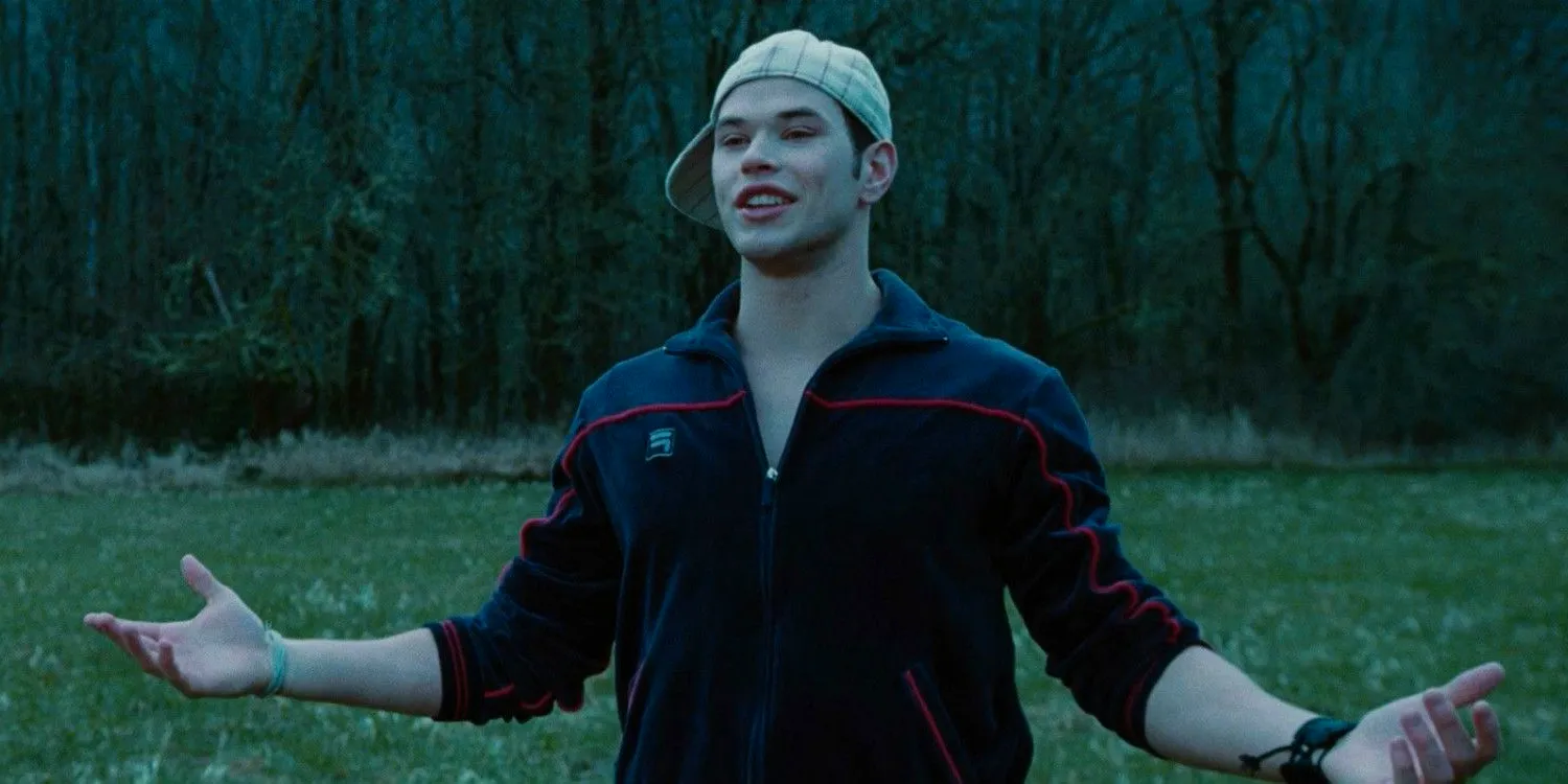 Emmett Cullen (Kellan Lutz) with his hat on sideways and his arms extended in a field in the baseball scene in the Twilight movie Image