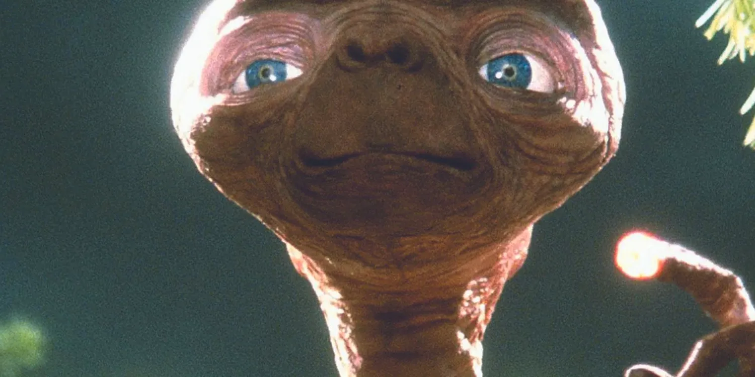 E.T. holds up a glowing finger in E.T. the Extra-terrestrial. Image