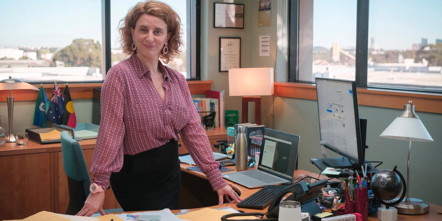 Felicity Ward as Hannah Howard sitting on a desk in Australian The Office remake-1 Image