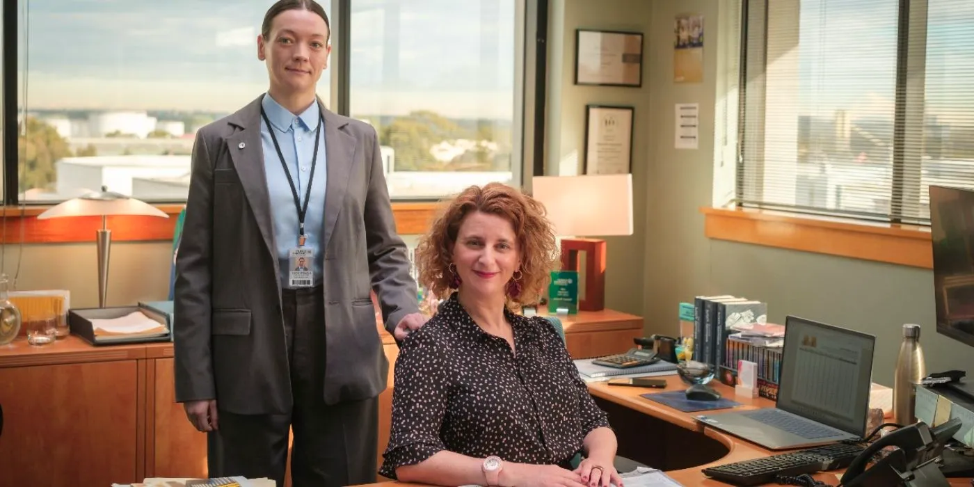 Felicity Ward sat at a desk with Edith Poor stood behind her in The Office Australia Image