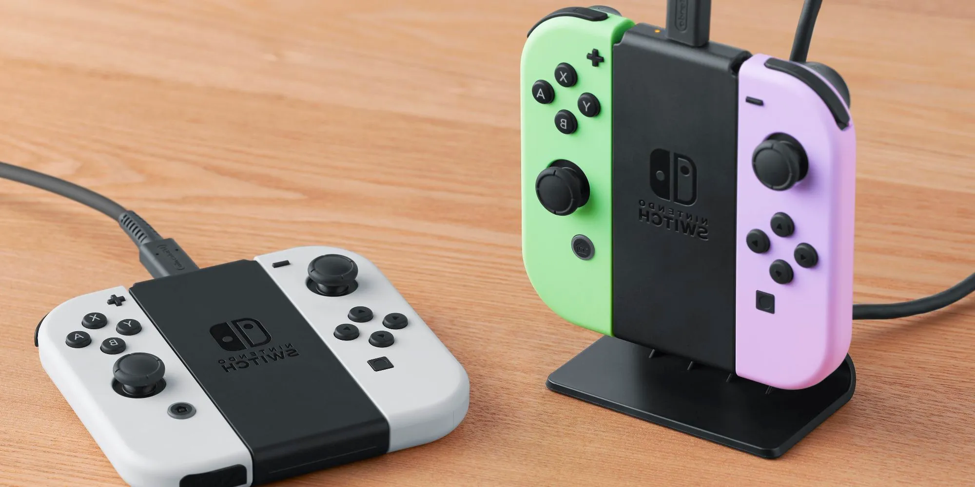 Four Joy-Cons being charged by two Joy-Con Charging Stands, on vertically on the stand itself, and the other removed from its stand laying flat. Image