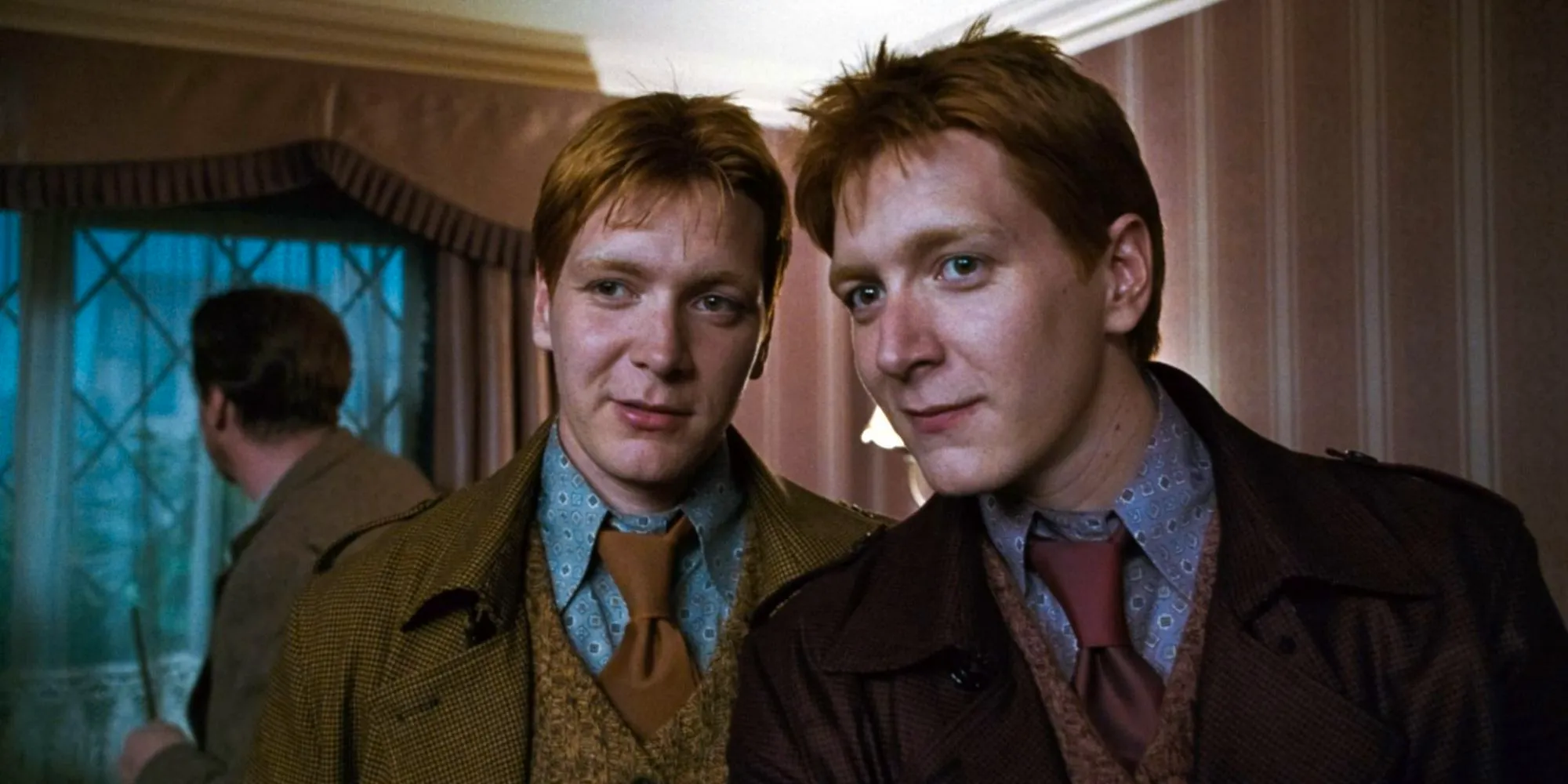 Fred (James Phelps) and George Weasley (Oliver Phelps) leaning in to one another in Harry Potter and the Deathly Hallows: Part 1 Image