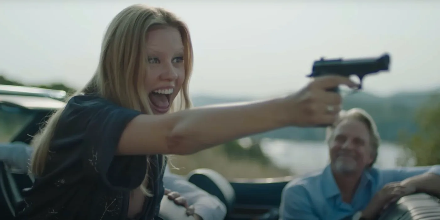 Gabi (Mia Goth) with Gun in Infinity Pool, she points it off frame with a crazed and joyeous expression on her face Image