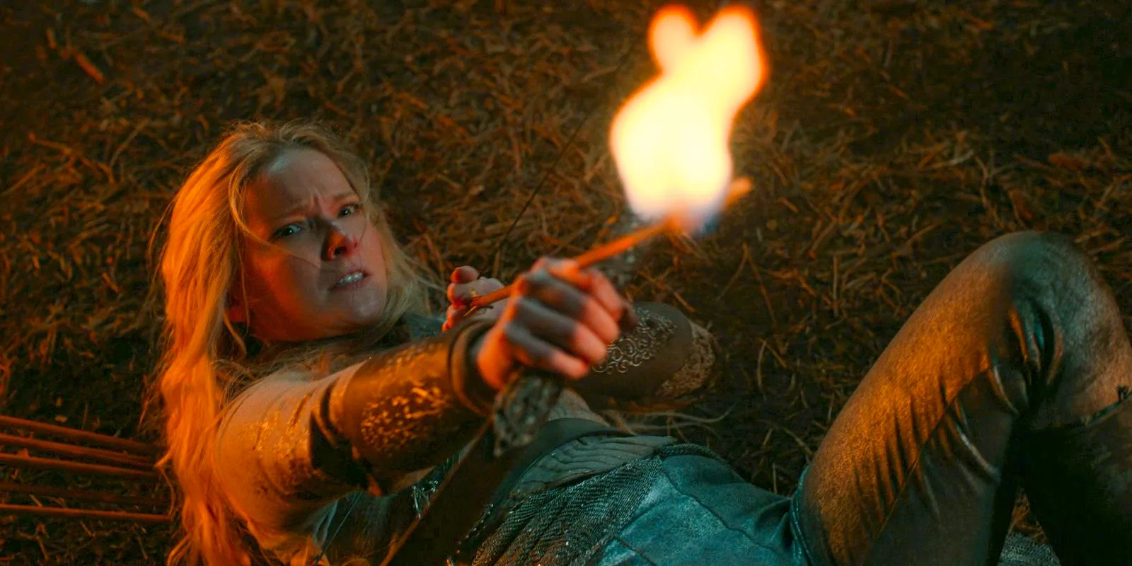 Galadriel (Morfydd Clark) on the ground, aiming a fire arrow at Adar in The Lord of the Rings: The Rings of Power. Image