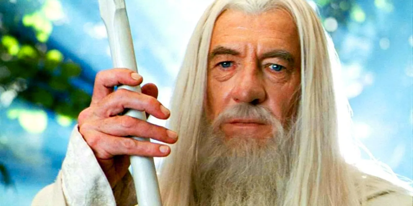 Gandalf the White holding his staff against a background of light in The Lord of the Rings Image