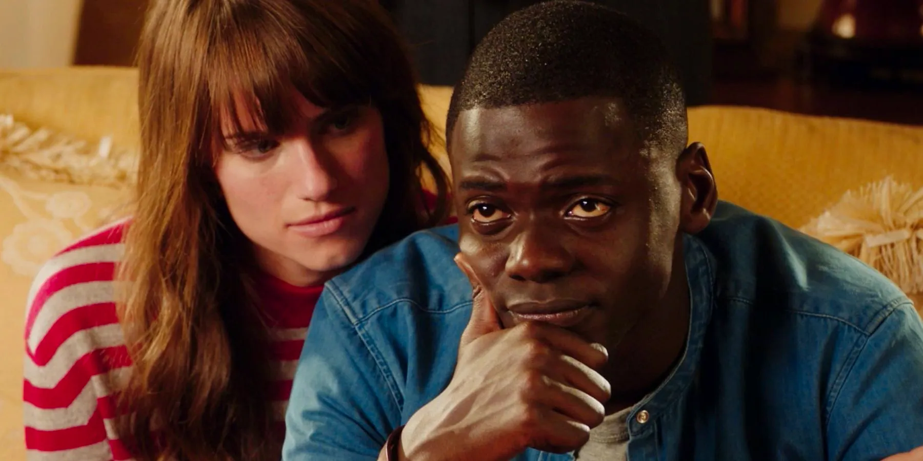 Get Out image with Daniel Kaluuya and Lake Bell sitting on a sofa. Image