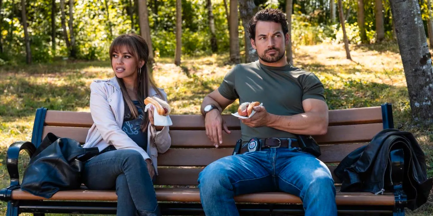 Giacomo Gianniotti as Cole Ellis and Vanessa Morgan as Max Mitchell eating lunch together on a bench in Wild Cards. Image