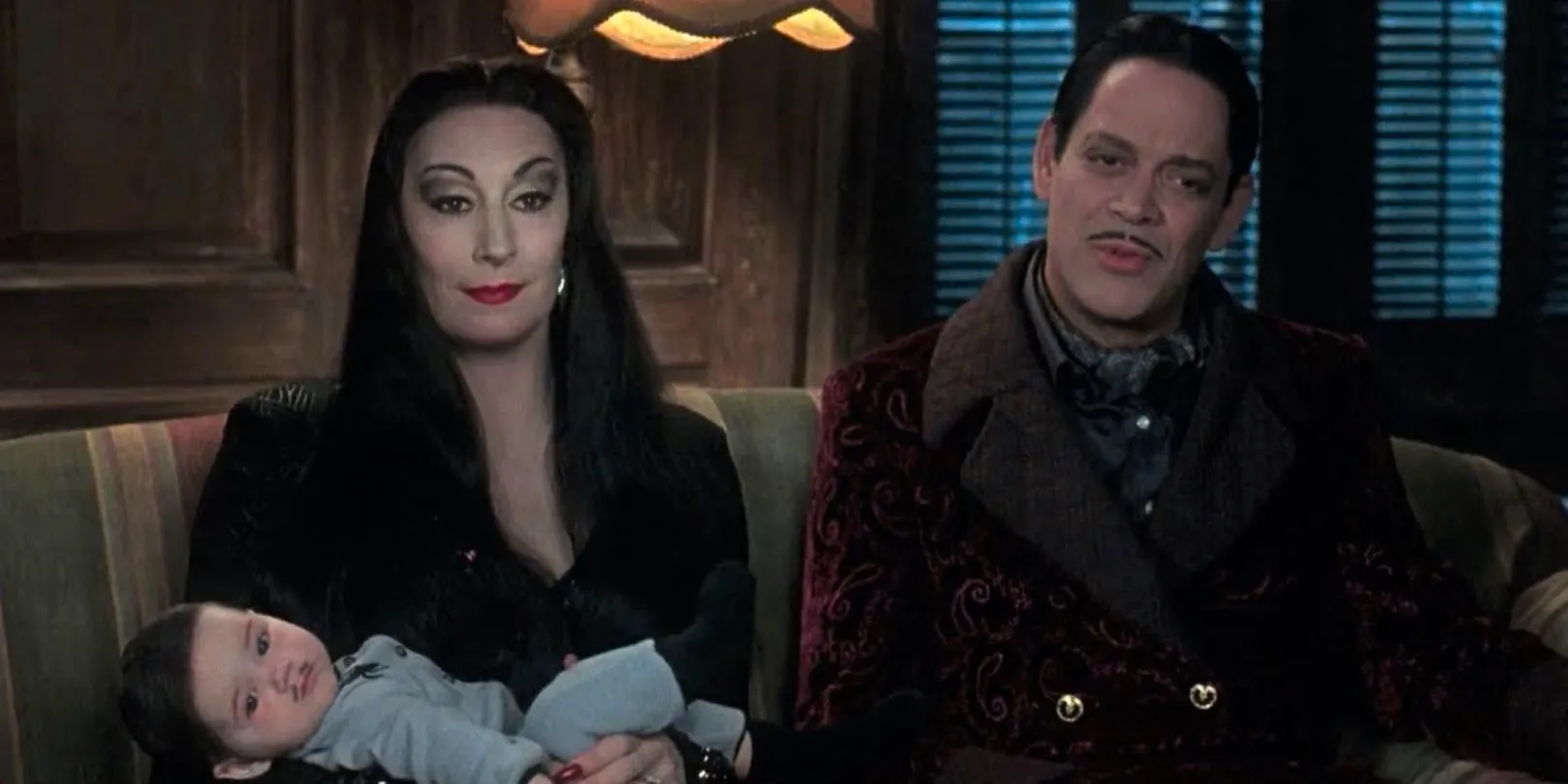 Gomez and Morticia sitting with baby Pubert on the sofa in Addams Family Values Image