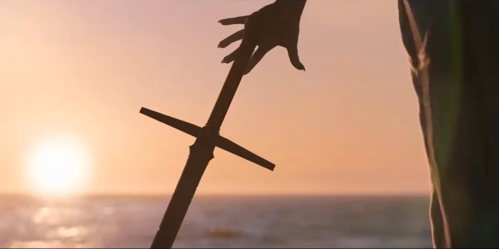 Gorr reaches for his sword in front of a rising sun in Thor Love and Thunder Image