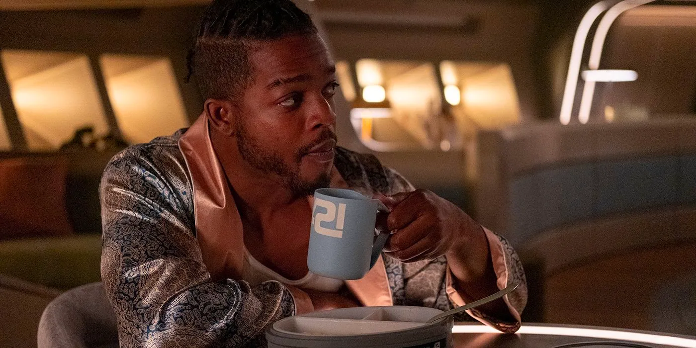 Halan holds his coffee mug while looking surprised in Beacon 23 season 1 Image