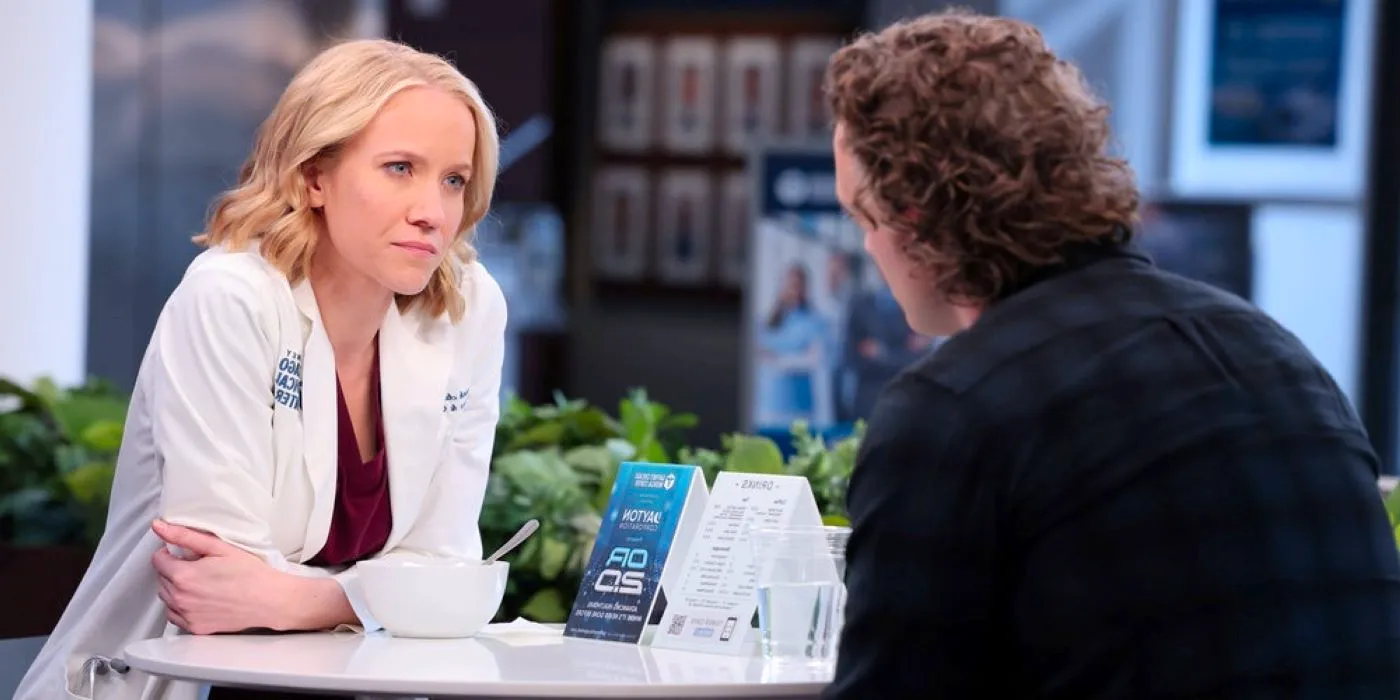 Hannah Asher and Sean Archer sit at a table in the hospital in Chicago Med season 8, episode 20. Image